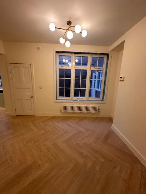 Renovated room with herringbone flooring and modern light fitting