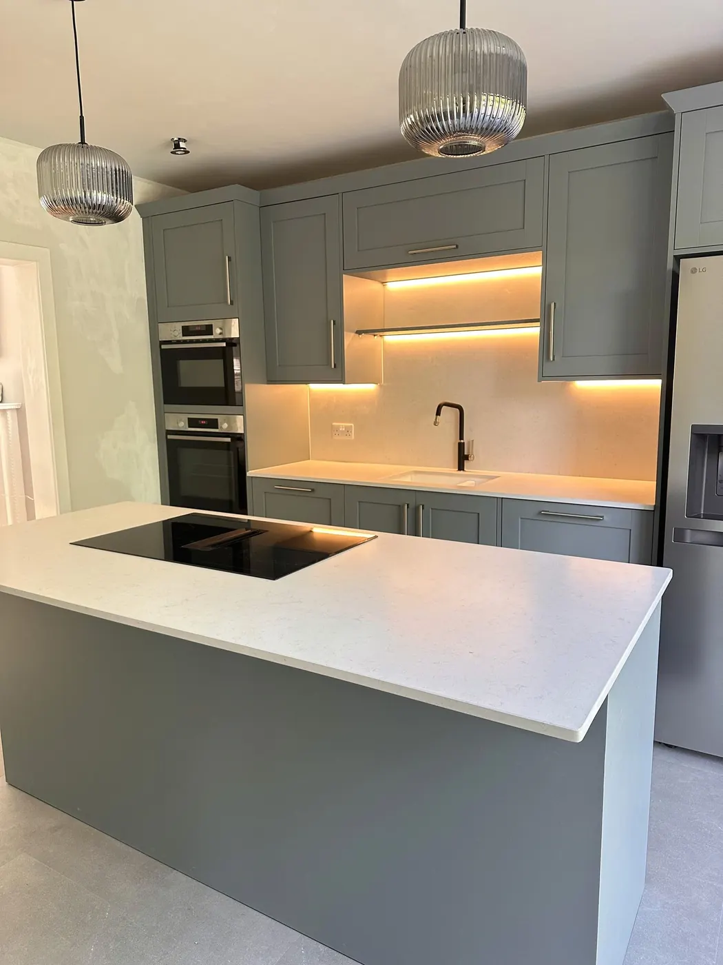 Grey-green kitchen renovation with island, quartz worktop and pendant lights